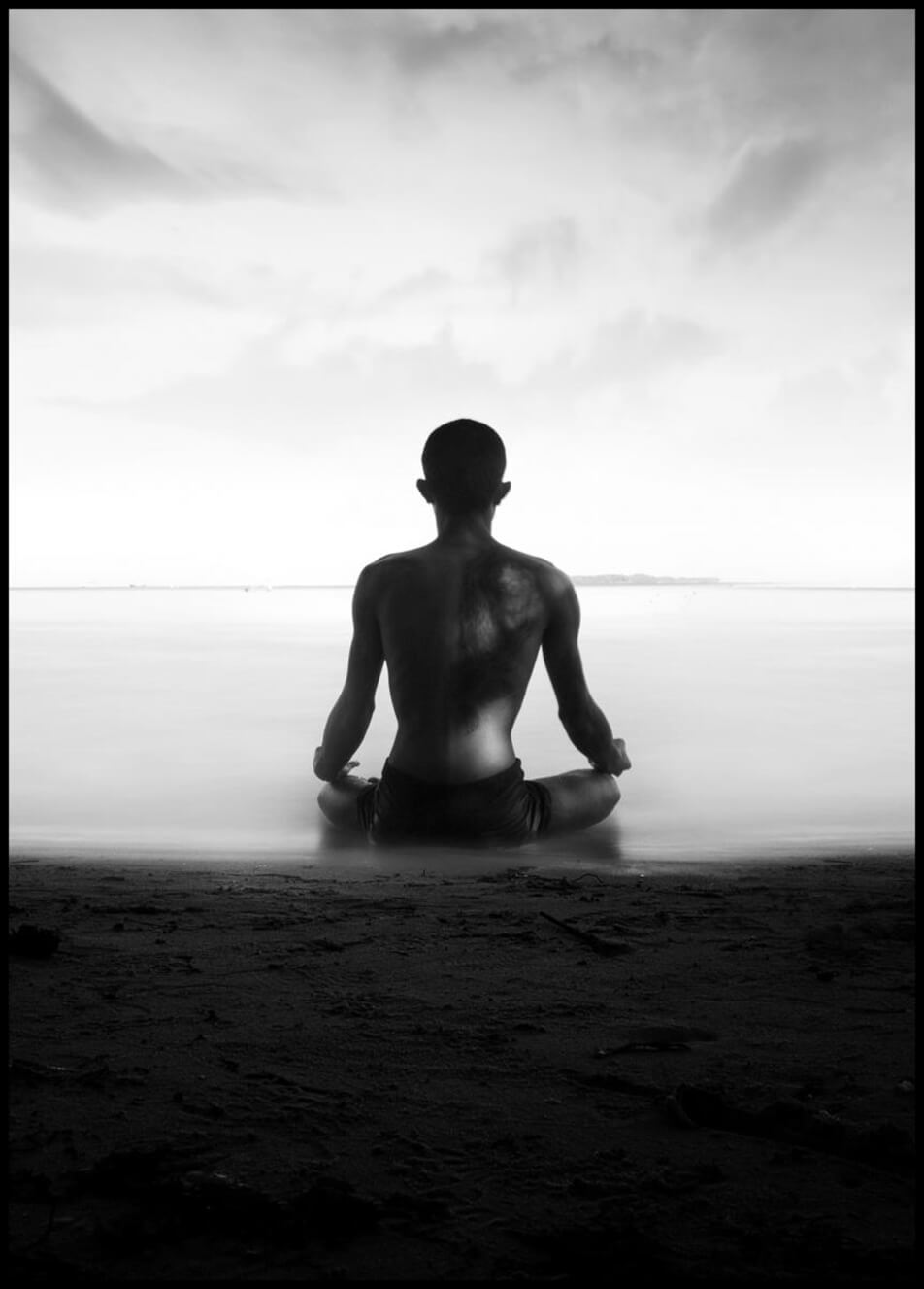 Poster met foto van een man die mediteert op het strand